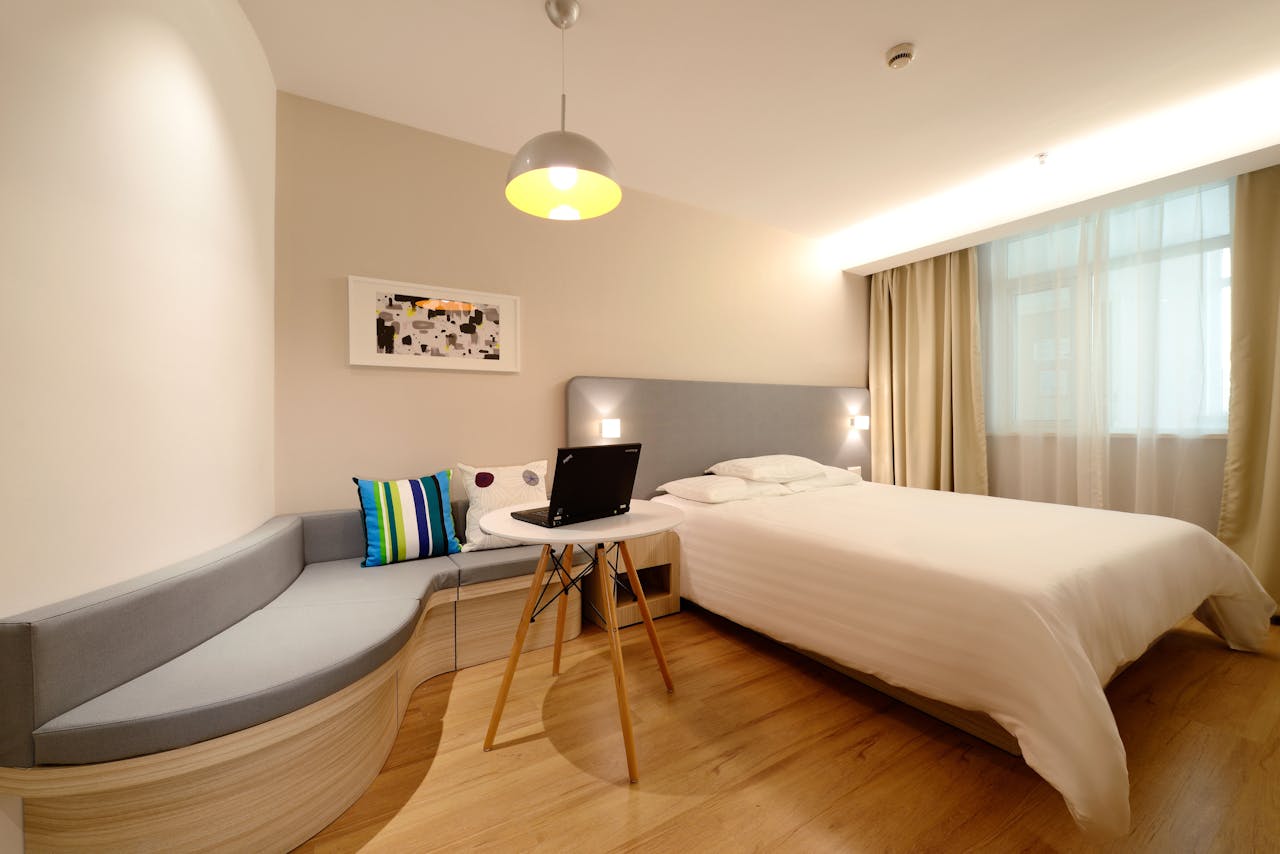 services-bg Modern hotel room featuring a bed, laptop, and stylish decor with ample lighting.