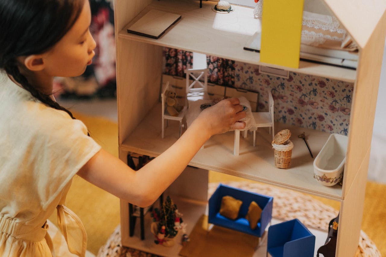 services-04 A young girl playing with a dollhouse indoors, showcasing childhood imagination and playtime.
